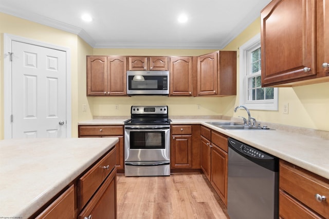 kitchen featuring light wood-type flooring, stainless steel appliances, ornamental molding, and sink