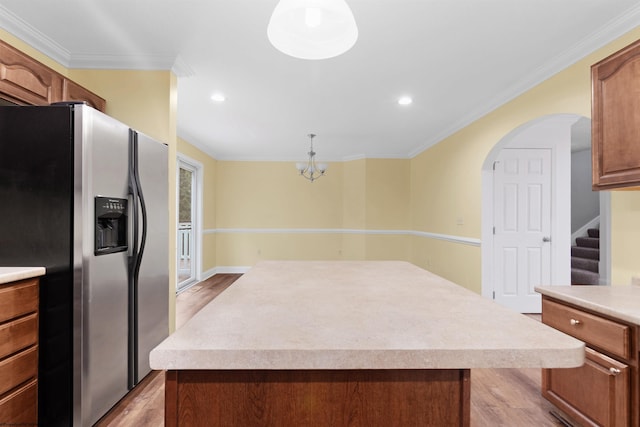 kitchen with stainless steel fridge, light hardwood / wood-style flooring, a kitchen island, and decorative light fixtures