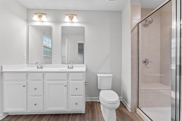 bathroom featuring hardwood / wood-style floors, vanity, a shower with shower door, and toilet