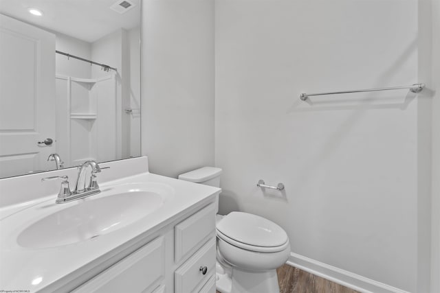 bathroom featuring walk in shower, hardwood / wood-style flooring, vanity, and toilet