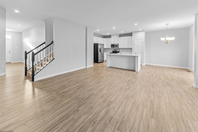 unfurnished living room featuring a chandelier and light wood-type flooring