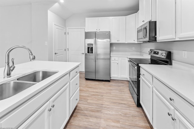 kitchen featuring light wood-type flooring, stainless steel appliances, vaulted ceiling, sink, and white cabinets