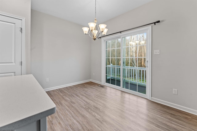 unfurnished dining area with a notable chandelier and wood-type flooring