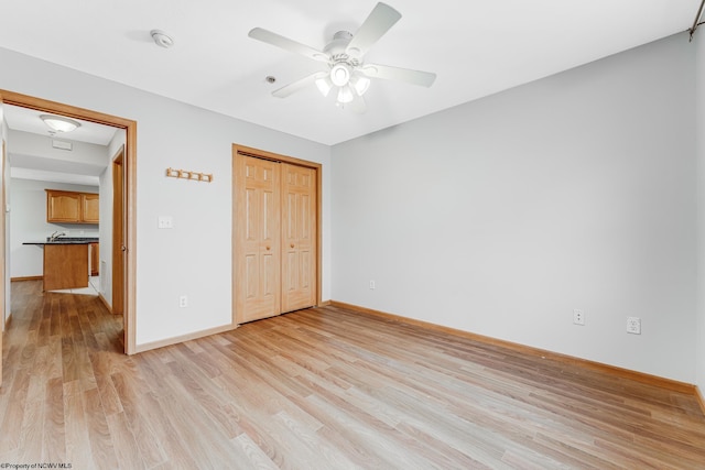 unfurnished bedroom with ceiling fan, a closet, and light wood-type flooring