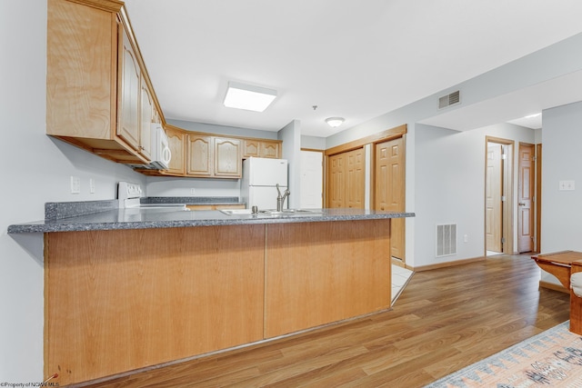 kitchen with sink, light hardwood / wood-style flooring, kitchen peninsula, stove, and white fridge