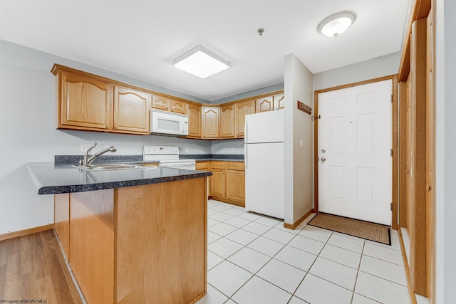 kitchen with kitchen peninsula, sink, light tile patterned floors, and white appliances