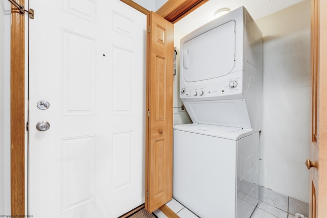 clothes washing area featuring stacked washer / drying machine and light tile patterned floors