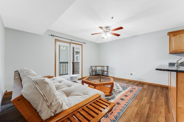 living room featuring ceiling fan, sink, and dark wood-type flooring