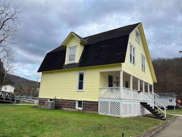 view of side of property with covered porch, central AC, and a lawn