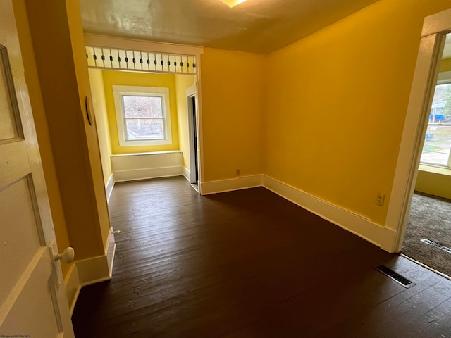 unfurnished room with dark hardwood / wood-style flooring and a healthy amount of sunlight