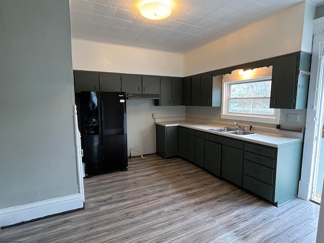 kitchen featuring black refrigerator with ice dispenser, sink, and light wood-type flooring