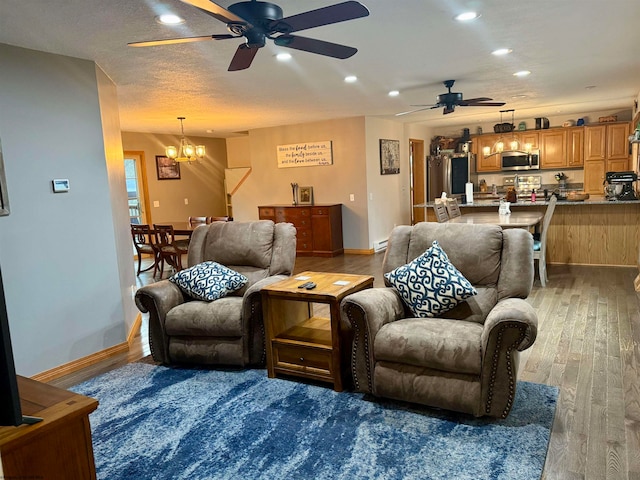 living room featuring a textured ceiling, ceiling fan with notable chandelier, and dark wood-type flooring