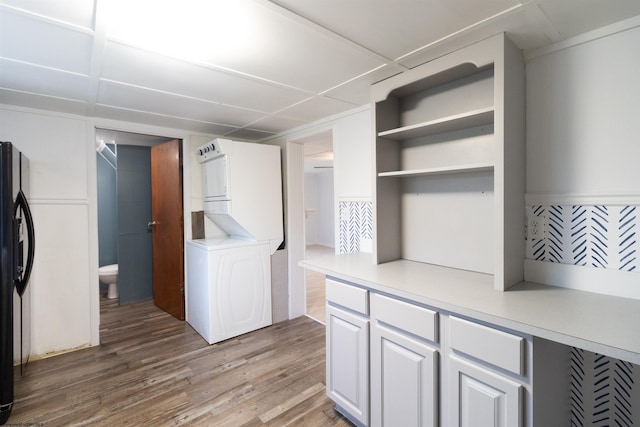 laundry area with hardwood / wood-style floors and stacked washer / drying machine