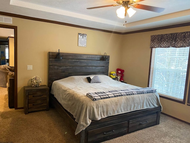 bedroom featuring ceiling fan, carpet floors, ornamental molding, and a tray ceiling