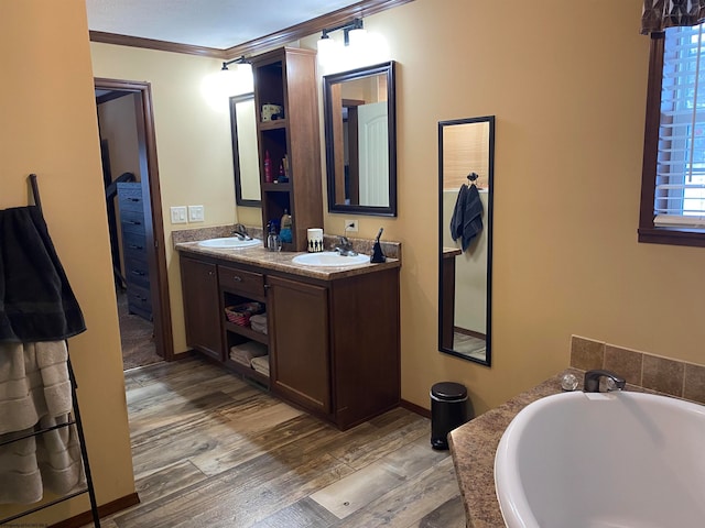 bathroom featuring a bathing tub, crown molding, vanity, and wood-type flooring