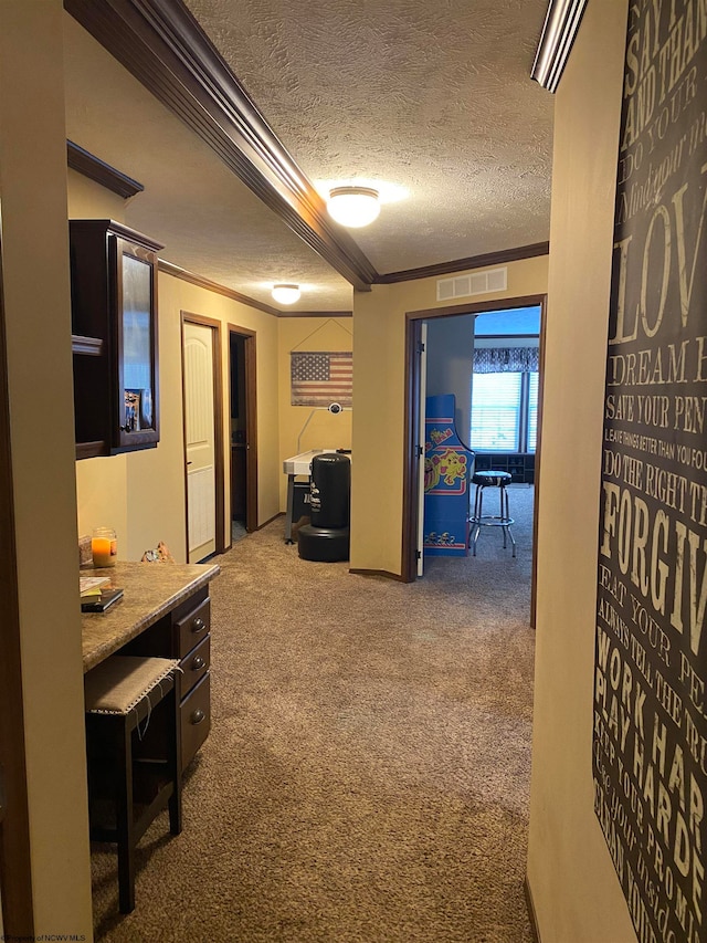 hallway featuring carpet, a textured ceiling, and ornamental molding