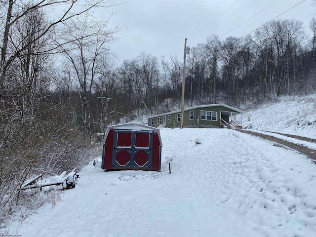 snowy yard featuring a storage shed