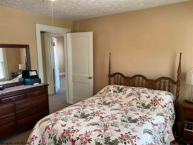 bedroom featuring a textured ceiling and dark carpet