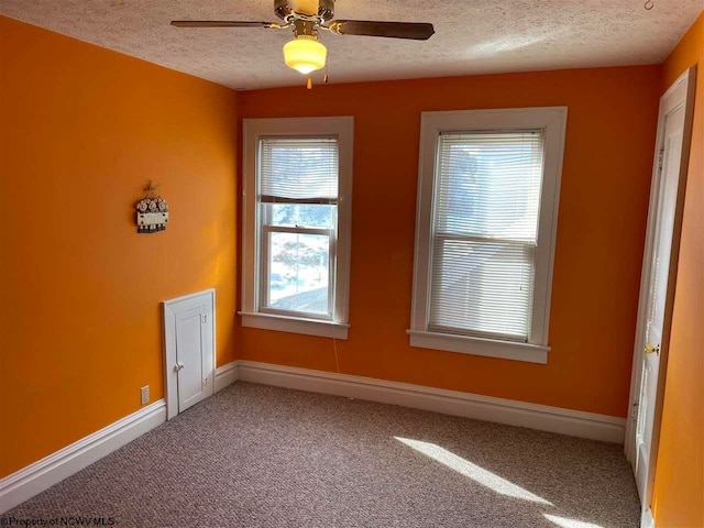 carpeted spare room featuring ceiling fan and a textured ceiling