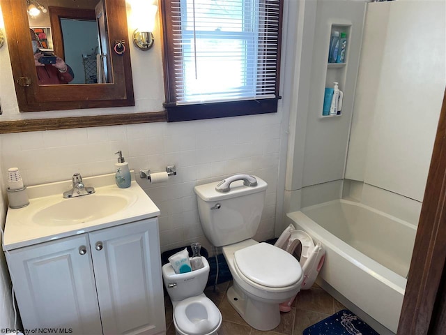 bathroom featuring toilet, vanity, tile patterned floors, and tile walls