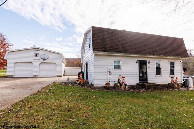 view of front of property with a front yard, a garage, central AC unit, and an outdoor structure