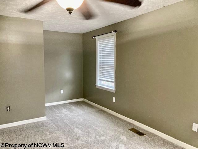 carpeted spare room with ceiling fan and a textured ceiling