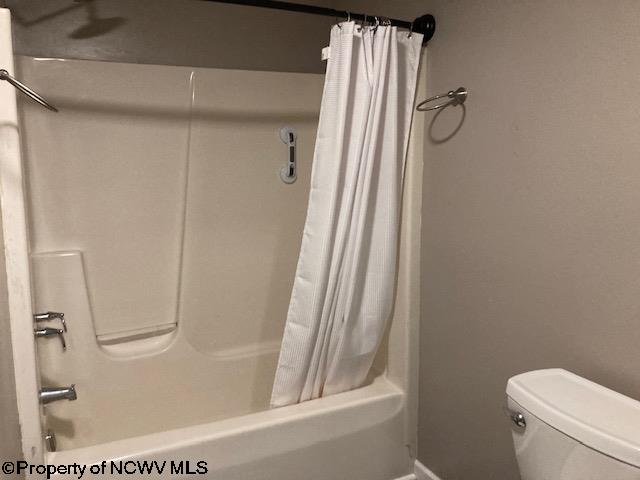 bathroom featuring shower / bath combo and toilet