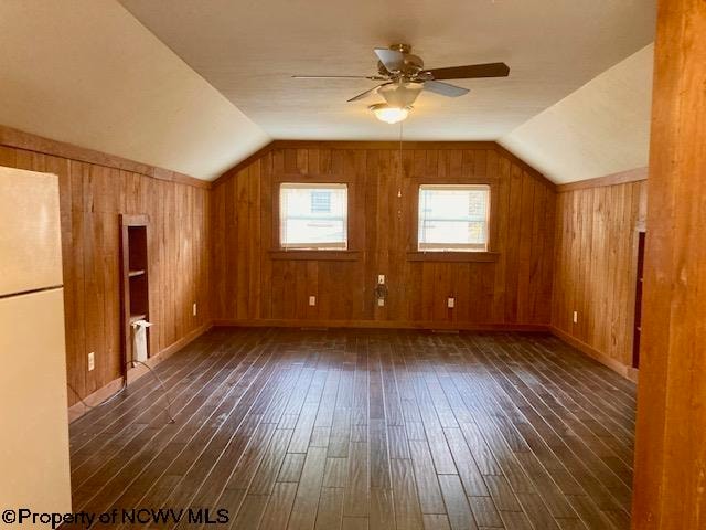 bonus room with dark hardwood / wood-style floors, vaulted ceiling, ceiling fan, and wooden walls