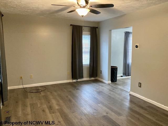 unfurnished room with ceiling fan, dark hardwood / wood-style flooring, and a textured ceiling