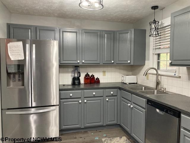 kitchen with gray cabinetry, sink, dark wood-type flooring, tasteful backsplash, and appliances with stainless steel finishes