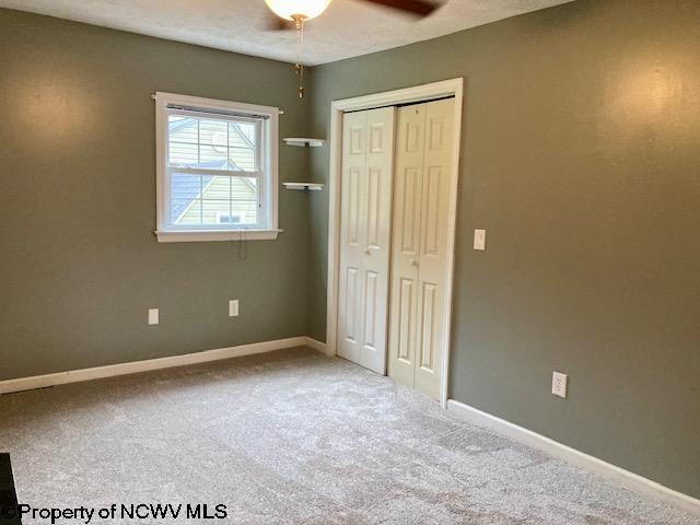 unfurnished bedroom with carpet flooring, ceiling fan, and a closet