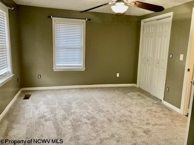 unfurnished bedroom with multiple windows, ceiling fan, and light carpet