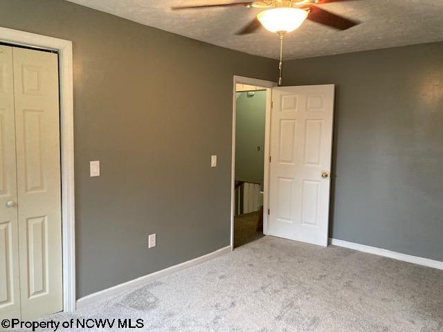 unfurnished bedroom featuring a textured ceiling, ceiling fan, light carpet, and a closet