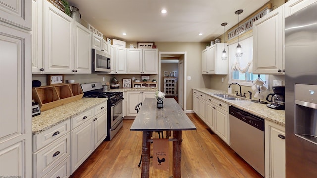 kitchen with white cabinetry, stainless steel appliances, decorative light fixtures, and hardwood / wood-style flooring