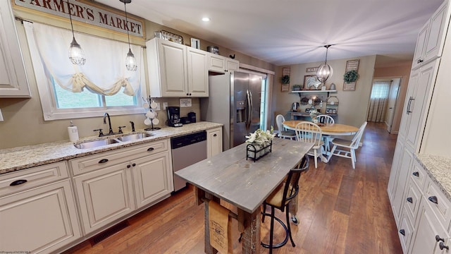 kitchen featuring sink, light stone countertops, decorative light fixtures, dark hardwood / wood-style flooring, and stainless steel appliances