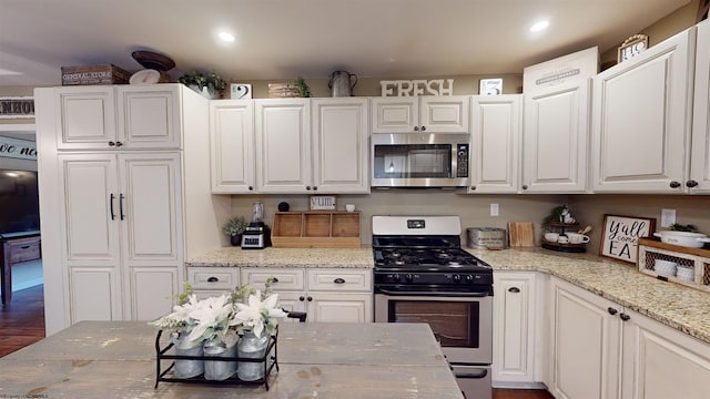 kitchen featuring white cabinets, dark hardwood / wood-style floors, light stone counters, and stainless steel appliances