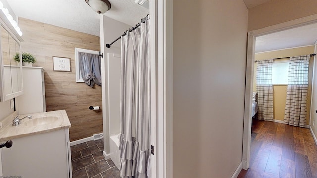 bathroom with wood-type flooring, a textured ceiling, shower / tub combo with curtain, vanity, and tile walls