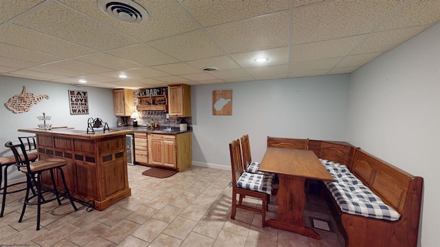 kitchen with decorative backsplash, a drop ceiling, and beverage cooler