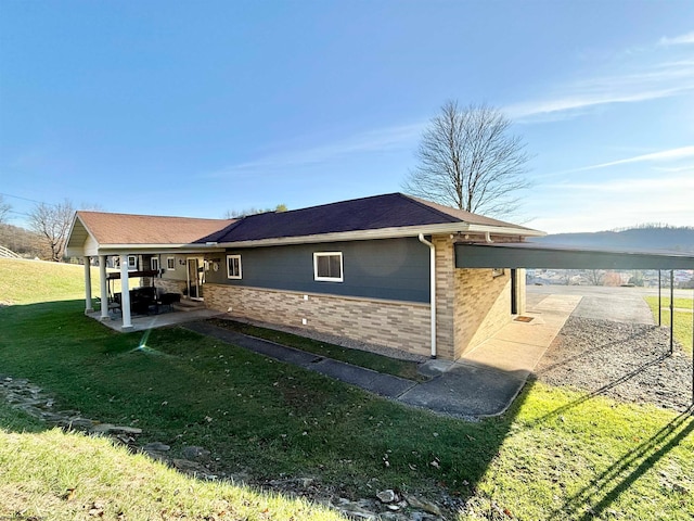 view of side of home featuring a lawn and a carport