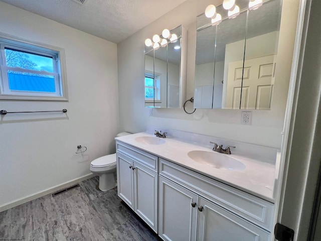 bathroom with vanity, wood-type flooring, a textured ceiling, and toilet