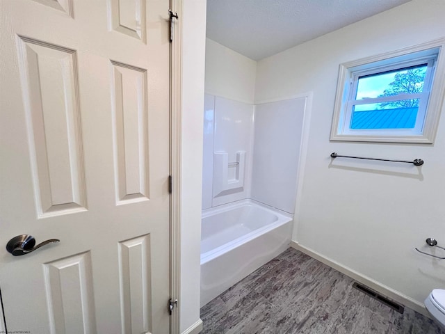 bathroom with hardwood / wood-style floors, bathtub / shower combination, and toilet