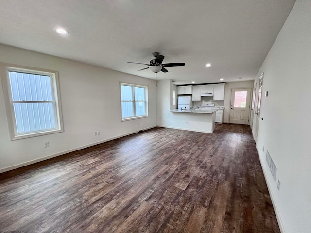 unfurnished living room featuring dark hardwood / wood-style floors, ceiling fan, and a wealth of natural light