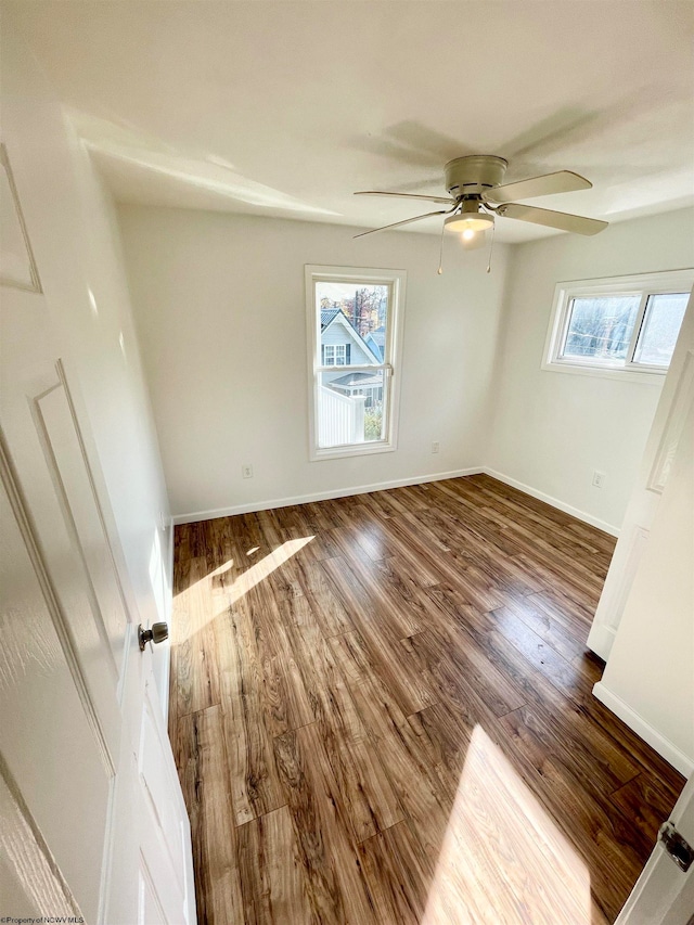 empty room featuring ceiling fan, wood-type flooring, and a wealth of natural light