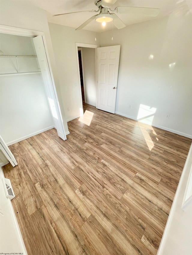 unfurnished bedroom with ceiling fan, a closet, and light hardwood / wood-style floors