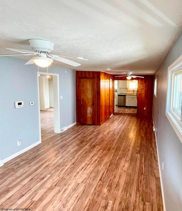 unfurnished living room with a textured ceiling, light hardwood / wood-style floors, ceiling fan, and sink