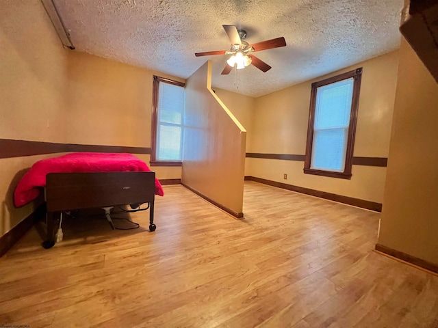 bedroom with ceiling fan, a textured ceiling, and light hardwood / wood-style flooring