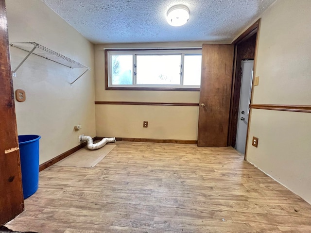 laundry area with light wood-type flooring and a textured ceiling