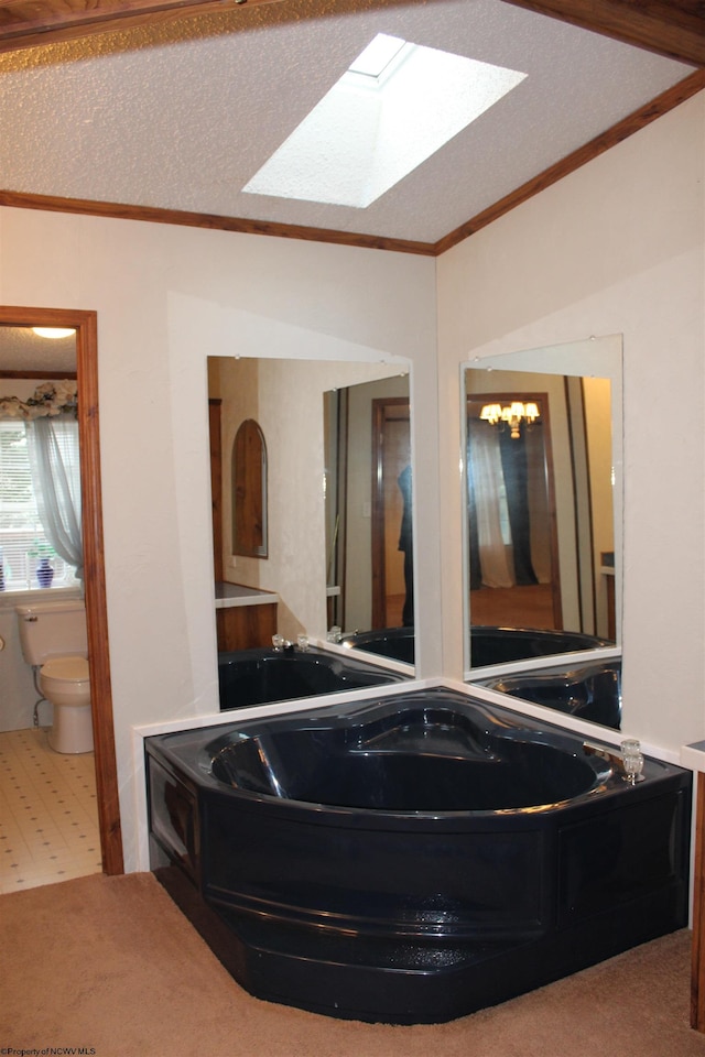 bathroom featuring a skylight, a textured ceiling, crown molding, toilet, and a bathing tub