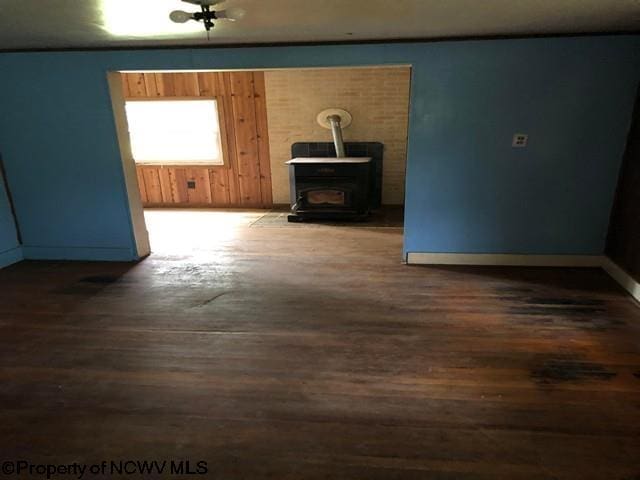 empty room featuring dark hardwood / wood-style floors, a wood stove, and wood walls