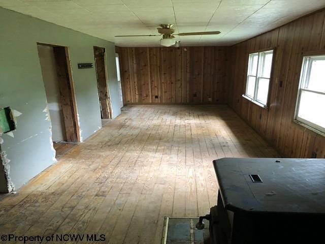 unfurnished room with wood walls, ceiling fan, and light hardwood / wood-style floors